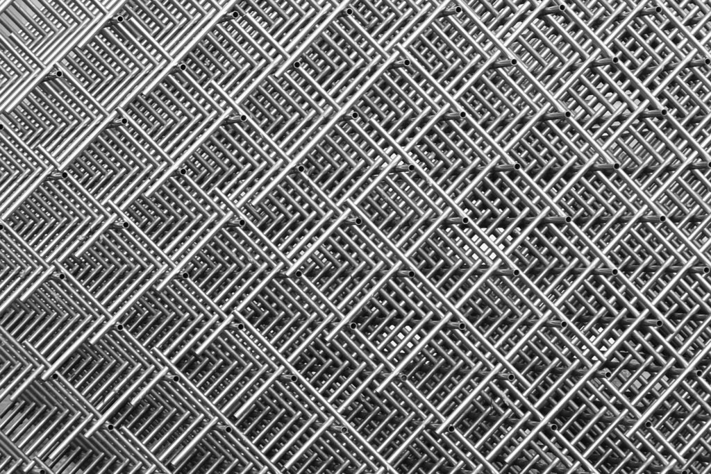 grid-wire-mesh-stainless-rods-rods-raster-35543 Abstract close-up of interwoven metal grids creating a symmetrical, textured pattern in monochrome.